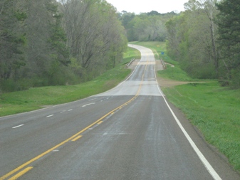 The subject was observed crossing the highway where the lighter and darker pavement transition occurs.